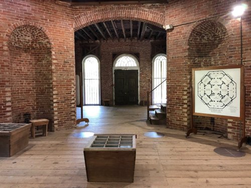Interior of a brick building featuring wooden floors, arched doorways, and a large map on display.