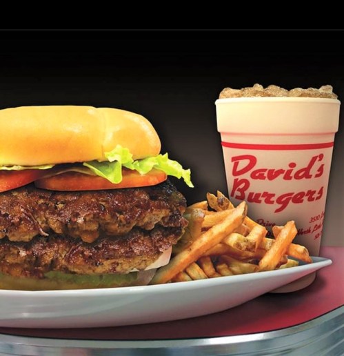 A juicy burger with lettuce and tomato, served with fries and a milkshake in a cup labeled "David's Burgers."