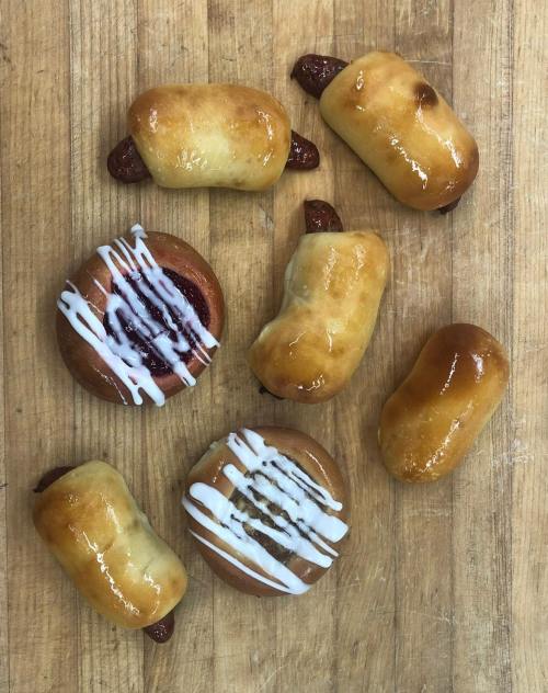 A variety of baked goods, including sweet rolls and pastries, arranged on a wooden surface.