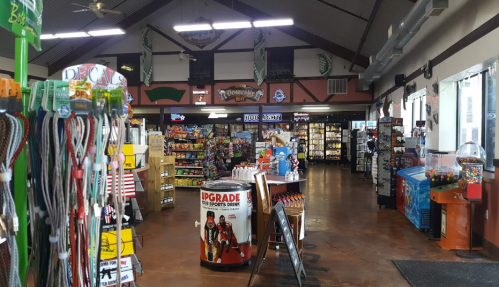 Interior of a convenience store with shelves of snacks, drinks, and merchandise, featuring a colorful candy machine.