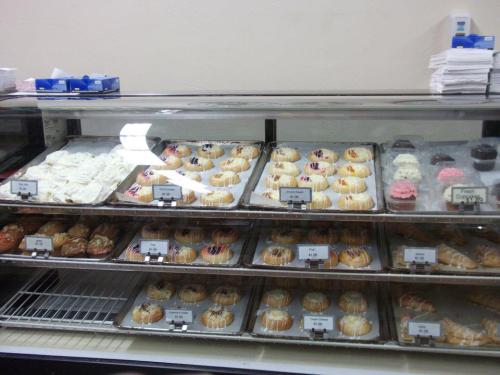 A display case filled with various baked goods, including pastries and cupcakes, neatly arranged on trays.