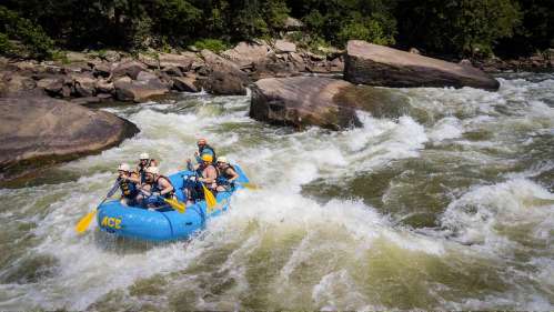 A group of people white-water rafting on a river, navigating through rapids and large rocks.