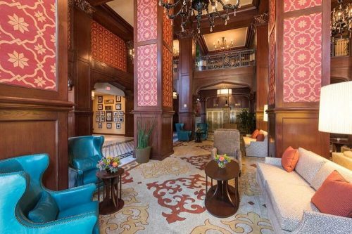 Elegant hotel lobby featuring ornate decor, plush seating, and vibrant floral arrangements. Warm, inviting atmosphere.