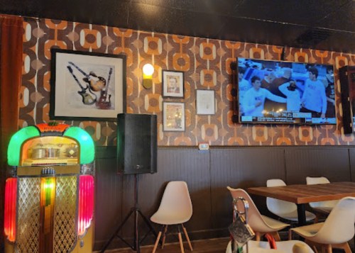 A retro jukebox, wall art, and a TV showing a sports game in a cozy restaurant setting.