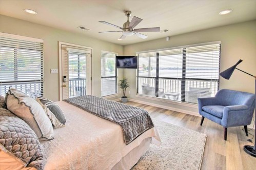 Bright bedroom with a large window, a bed with decorative pillows, a blue chair, and a ceiling fan.
