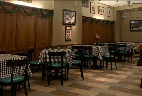 A cozy restaurant interior with checkered tablecloths, wooden walls, and festive decorations.