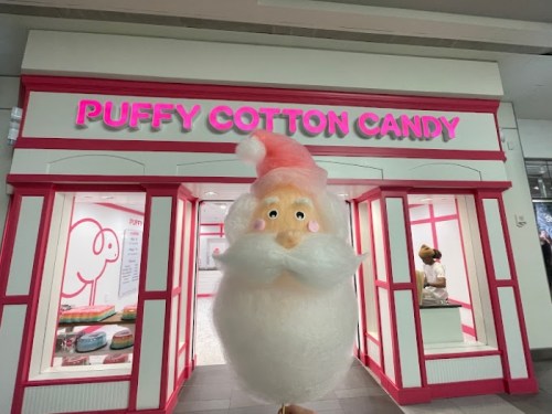 A whimsical storefront for "Puffy Cotton Candy" featuring a large, fluffy Santa figure with a pink hat and mustache.