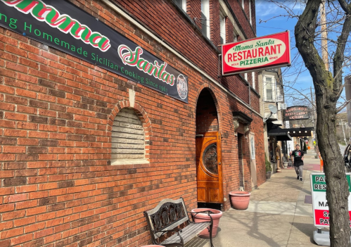 Exterior of Mama Santa's Restaurant and Pizzeria, featuring brick walls and a sign for homemade Sicilian cooking.