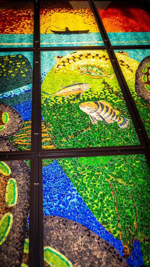 Colorful mosaic artwork featuring fish, lizards, and vibrant patterns in green, blue, and orange tones.