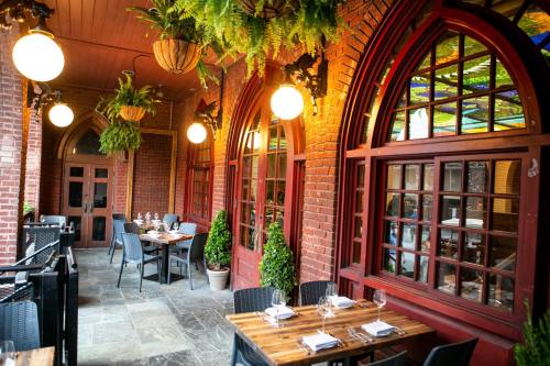 Cozy restaurant patio with brick walls, arched windows, hanging plants, and wooden tables set for dining.