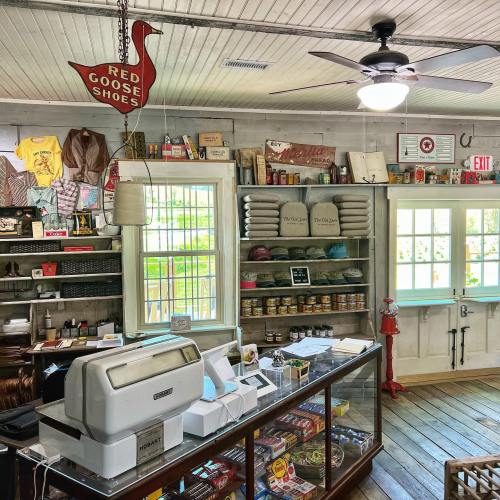 A cozy shop interior featuring vintage decor, shelves of goods, and a cash register near the entrance.