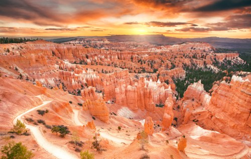 Sunset over Bryce Canyon, showcasing vibrant orange rock formations and a winding path through the stunning landscape.
