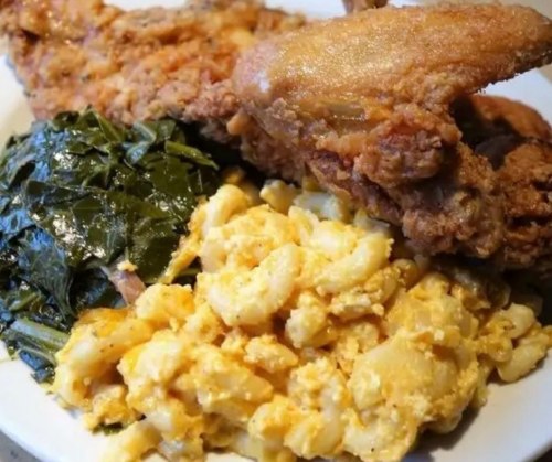 A plate of fried chicken, collard greens, and creamy macaroni and cheese.