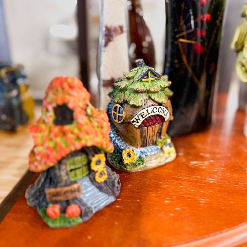 Two decorative miniature houses with colorful roofs and a "Welcome" sign, placed on a wooden surface.