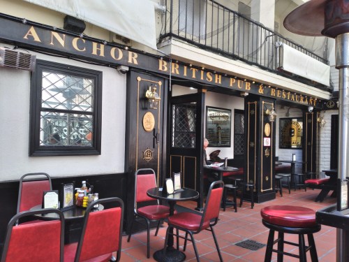 Exterior of the Anchor British Pub & Restaurant, featuring black and gold signage, outdoor seating, and a welcoming atmosphere.