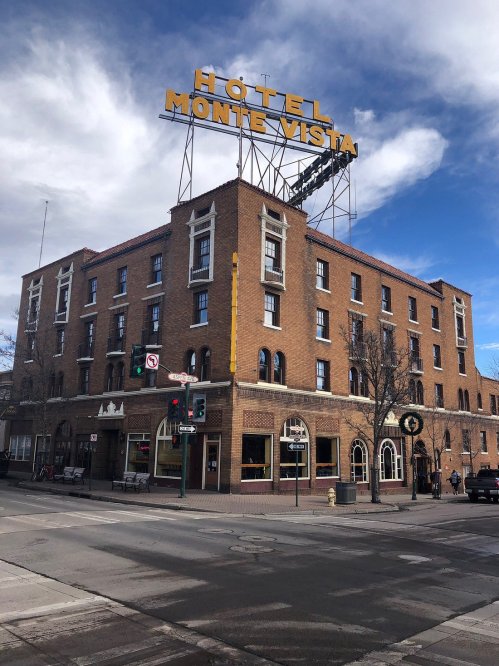 Historic Hotel Monte Vista with a prominent sign, featuring a brick facade and a clear blue sky in the background.