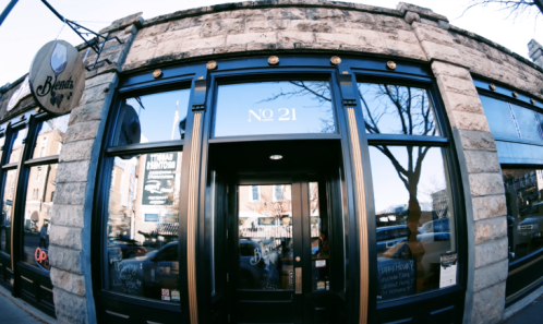 Exterior of a stone building with large windows, featuring a sign that reads "Bene's" and the number "21."