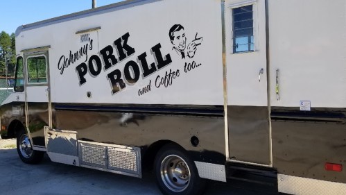 A food truck with the sign "Johnny's Pork Roll and Coffee too," featuring a vintage design and shiny exterior.