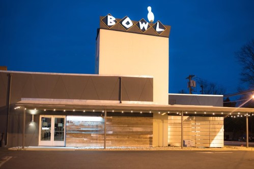 Exterior of a bowling alley named "Bowl," illuminated at night with a clear sky and modern design elements.