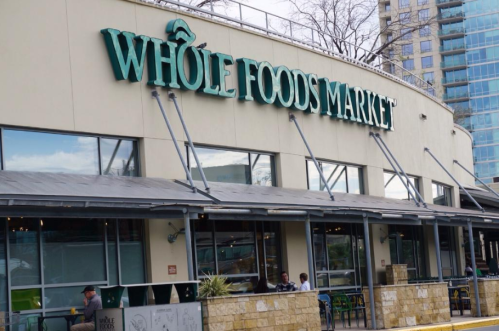 Exterior of a Whole Foods Market store with large signage and outdoor seating area.