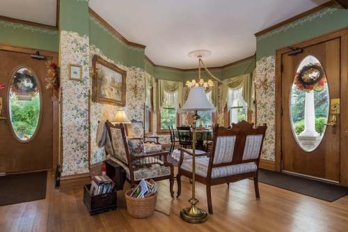 Cozy entryway with floral wallpaper, wooden doors, vintage furniture, and a lamp, creating a warm, inviting atmosphere.