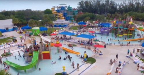 Aerial view of a vibrant water park with slides, pools, and families enjoying the attractions on a sunny day.