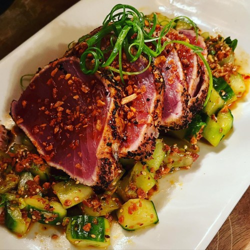 Seared tuna steak topped with green onions, served on a bed of diced cucumbers and garnished with crispy garlic.
