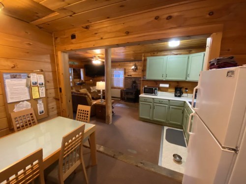 Cozy wooden cabin interior featuring a kitchen, dining area, and living space with rustic decor.