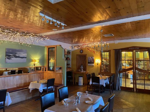 Cozy restaurant interior with wooden ceiling, tables set for dining, and warm lighting creating an inviting atmosphere.
