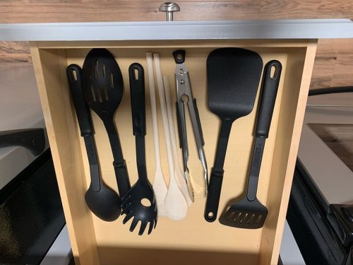 A kitchen drawer filled with various cooking utensils, including spatulas, spoons, and tongs, all neatly arranged.