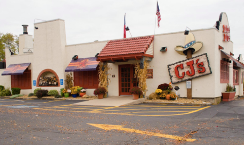 Exterior of CJ's restaurant featuring a red roof, decorative plants, and a sign with a cowboy hat.