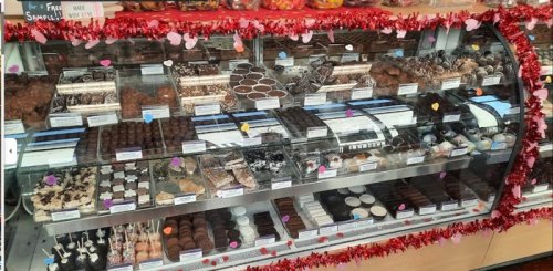 A display case filled with various chocolates and confections, decorated with festive garlands and colorful labels.