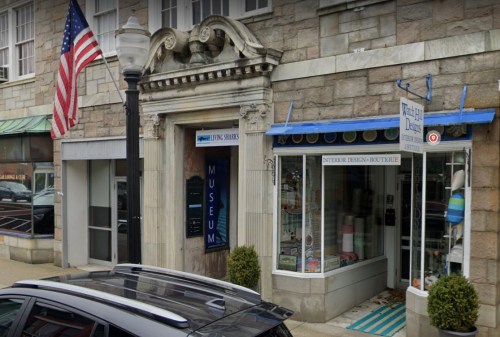 A stone building with a museum entrance and a boutique, featuring an American flag and colorful window displays.