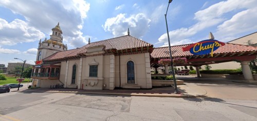 A colorful restaurant with a tiled roof and decorative architecture, set against a cloudy sky.