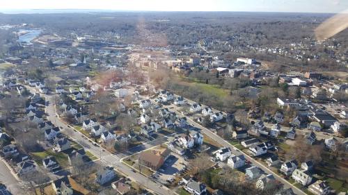 Aerial view of a suburban area with houses, streets, and green spaces under a clear blue sky.