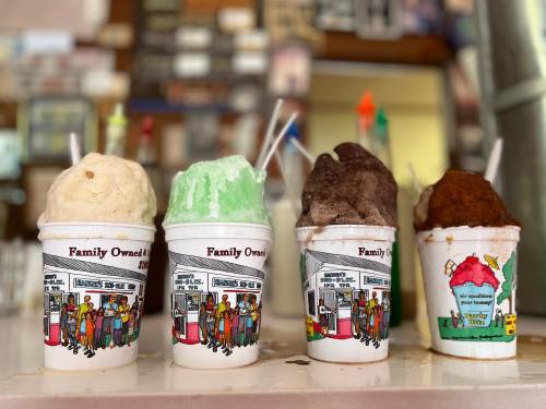Four colorful ice cream cups with different flavors, displayed on a counter in a family-owned shop.