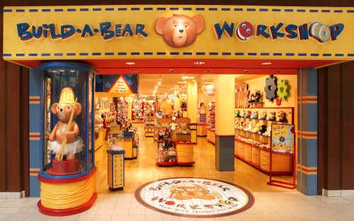 Entrance of a Build-A-Bear Workshop, featuring colorful signage and a display of stuffed animals inside.