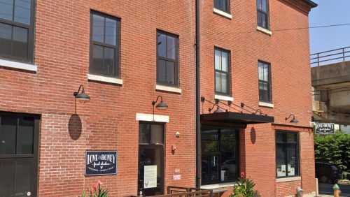 A brick building with large windows and a sign for "Love & Honey" on the front, surrounded by greenery.