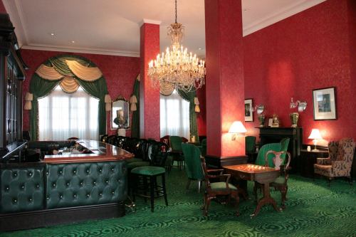 Elegant lounge with red walls, green furnishings, a chandelier, and a cozy seating area.