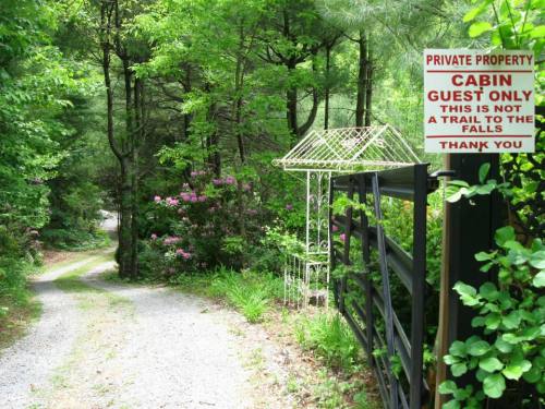 A gravel path leads through lush greenery, with a sign indicating private property and cabin access only.