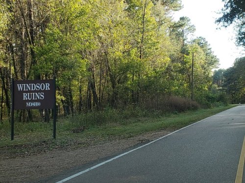Sign for Windsor Ruins along a tree-lined road, surrounded by greenery.