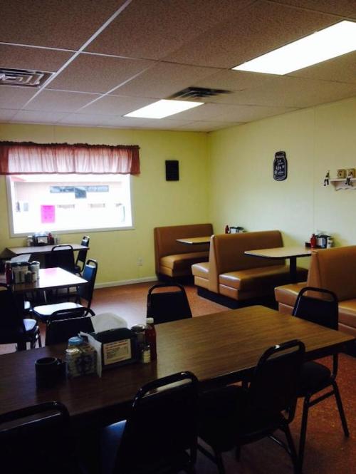 Cozy diner interior with yellow walls, booths, and tables, featuring simple decor and a warm atmosphere.