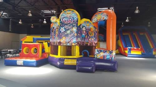 A colorful indoor bounce house with slides and play areas, featuring a vibrant design and various inflatable structures.
