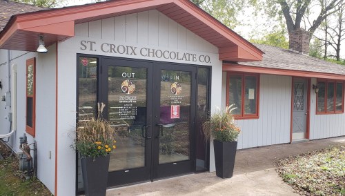 Exterior of St. Croix Chocolate Co. with a welcoming entrance and planters on either side.