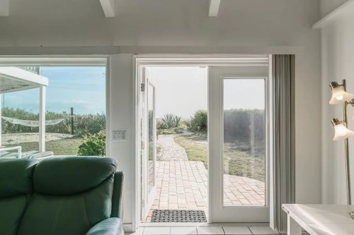 A view from inside a bright room, showing an open door leading to a pathway and outdoor greenery.