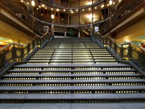 Staircase with illuminated steps and ornate railings in a historic building, featuring a warm, inviting ambiance.