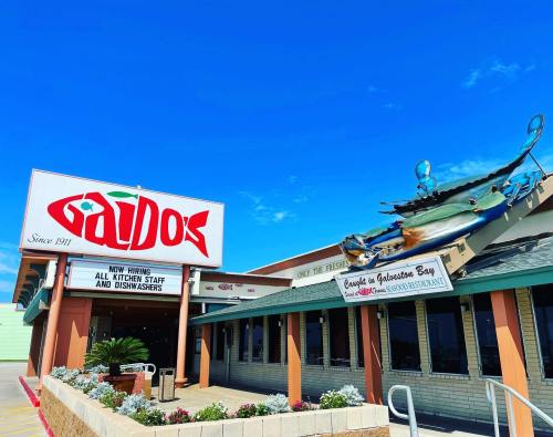 A seafood restaurant exterior with a large fish sign, announcing job openings and featuring a colorful fish sculpture.