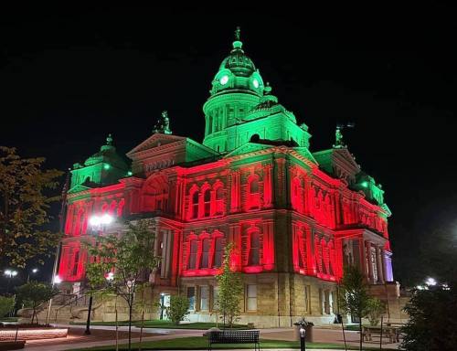 Historic building illuminated in red and green lights at night, showcasing its architectural details.
