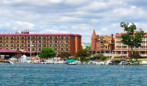 A waterfront view featuring hotels, boats, and lush greenery under a cloudy sky.