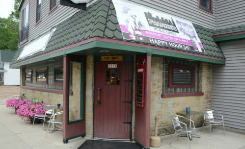 Exterior of Frankie's Pub & Grill, featuring a welcoming entrance and colorful flower planters. Happy Hour sign visible.